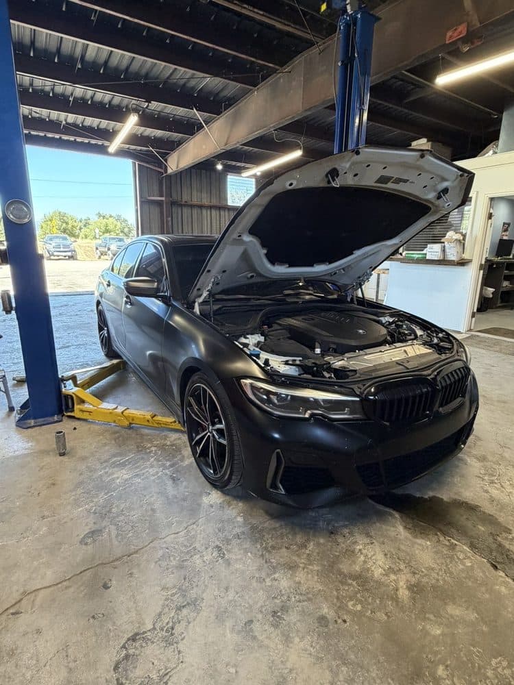 BMW 3-series raised on the lift with the hood open at NorCal Precision Auto in Redding, CA