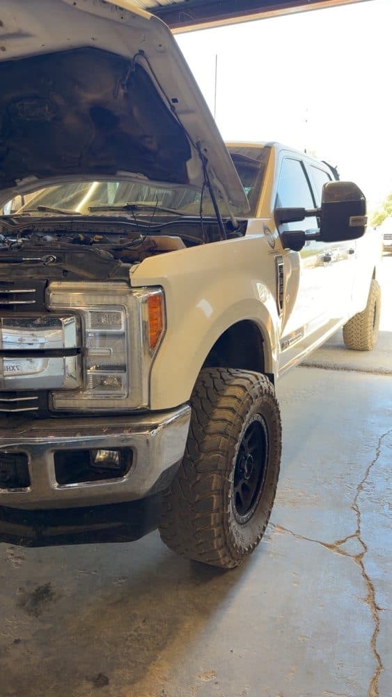 Two-tone Ford Super Duty with the hood raised for engine service at NorCal Precision Auto in Redding, CA